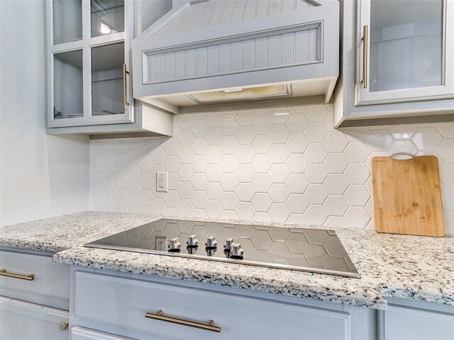 kitchen featuring premium range hood, decorative backsplash, black electric stovetop, and light stone countertops