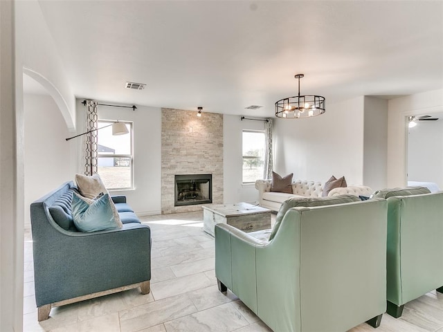 living room with a large fireplace, an inviting chandelier, and a wealth of natural light