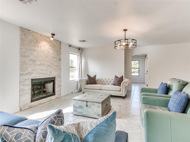 living room featuring a stone fireplace and an inviting chandelier