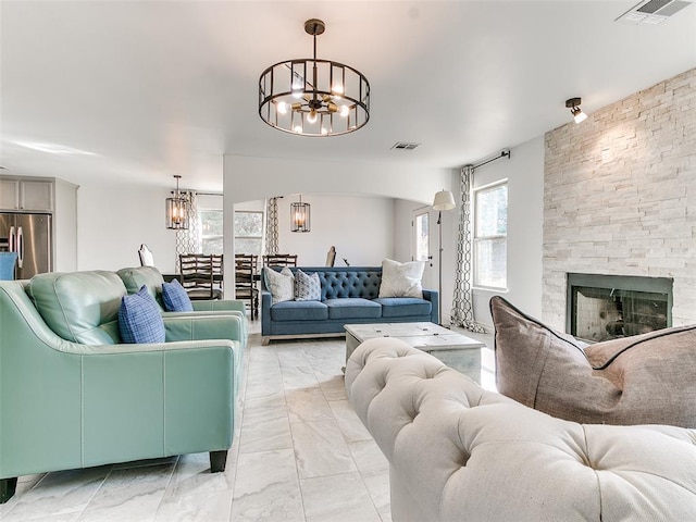 living room featuring a stone fireplace and a notable chandelier