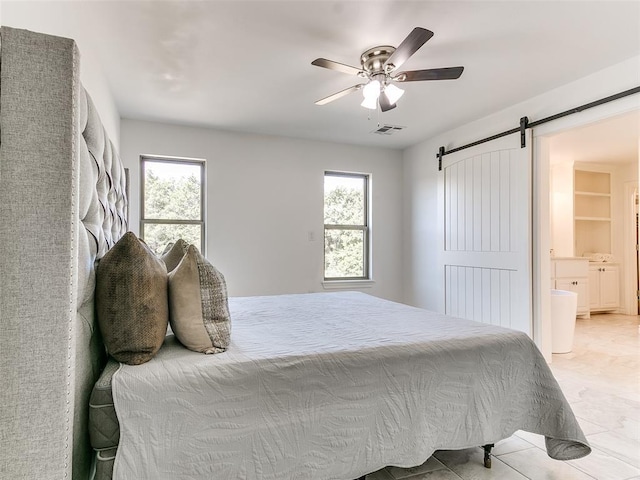 bedroom with ceiling fan, a barn door, and ensuite bathroom