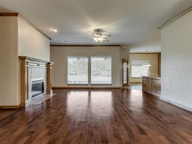 unfurnished living room with a fireplace, dark hardwood / wood-style flooring, ceiling fan with notable chandelier, and ornamental molding