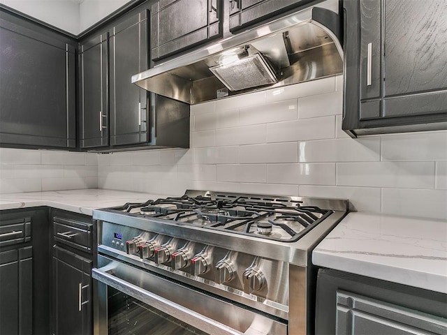 kitchen featuring light stone counters, tasteful backsplash, and high end stainless steel range oven