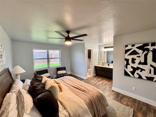 bedroom with ceiling fan, light hardwood / wood-style flooring, connected bathroom, and a textured ceiling