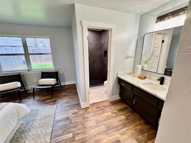 bathroom featuring vanity, hardwood / wood-style floors, a shower, and toilet