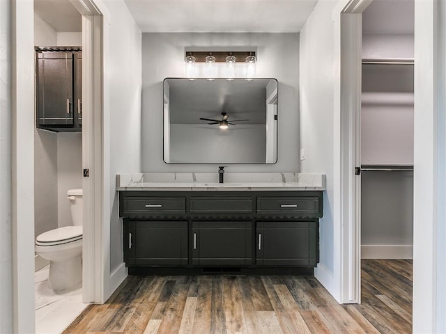 bathroom with hardwood / wood-style floors, vanity, toilet, and ceiling fan