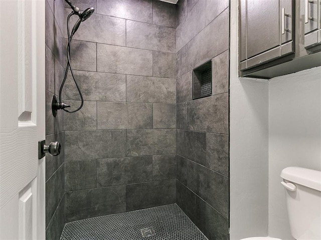 bathroom featuring a tile shower and toilet