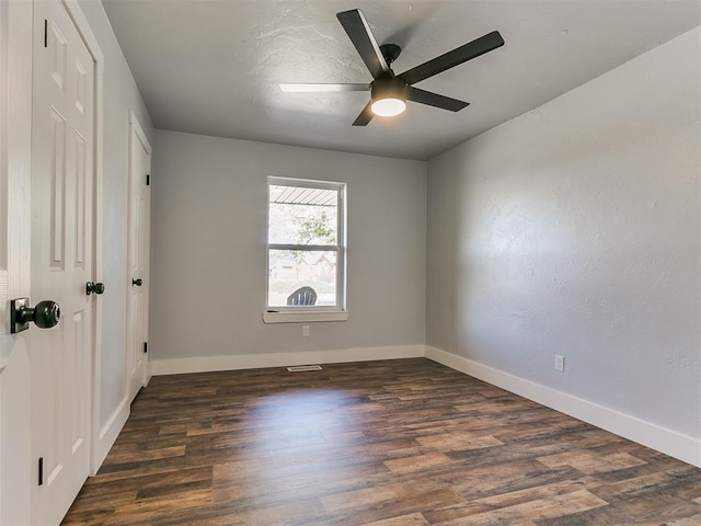 spare room with dark wood-type flooring and ceiling fan