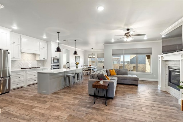 kitchen with a breakfast bar area, white cabinets, a kitchen island with sink, and appliances with stainless steel finishes