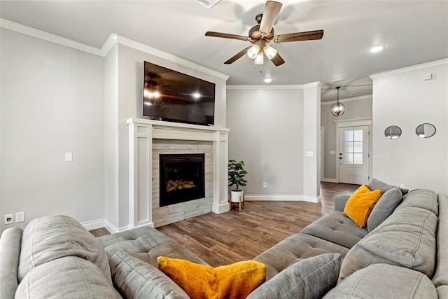 living room featuring ceiling fan, a tile fireplace, crown molding, and hardwood / wood-style flooring