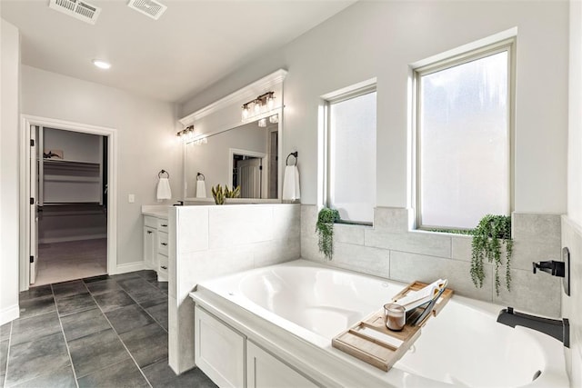 bathroom featuring tile patterned flooring, a tub to relax in, and vanity