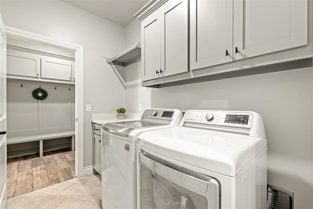 laundry room with cabinets, washing machine and clothes dryer, and light tile patterned floors