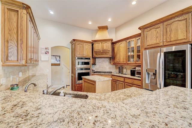 kitchen featuring stainless steel appliances, light stone countertops, sink, and backsplash