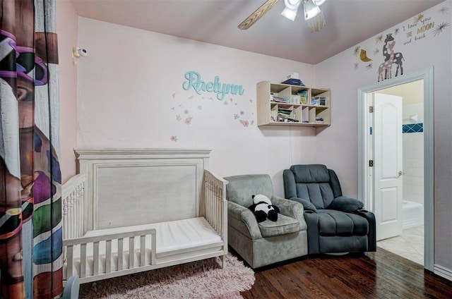 bedroom featuring dark hardwood / wood-style flooring, a nursery area, and ceiling fan