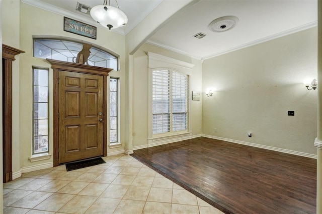 entryway with ornamental molding and light tile patterned floors