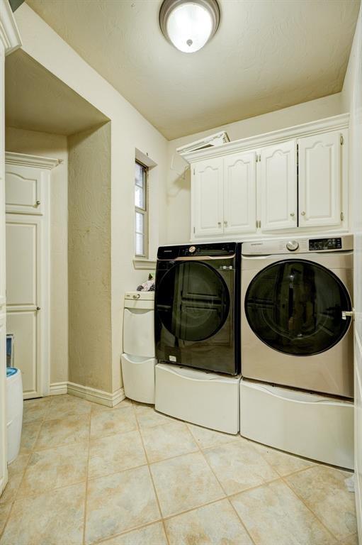 laundry room with cabinets, washer and dryer, and light tile patterned floors