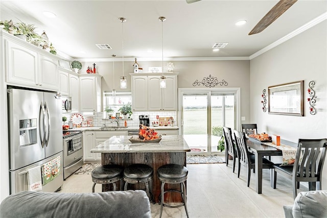 kitchen with pendant lighting, sink, a kitchen island, white cabinetry, and stainless steel appliances