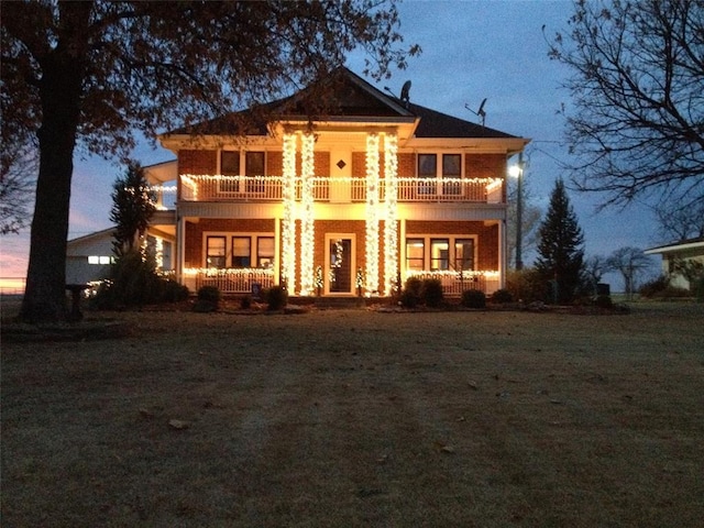 view of front facade featuring covered porch, a balcony, and a yard