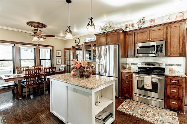 kitchen featuring appliances with stainless steel finishes, dark hardwood / wood-style floors, light stone counters, and hanging light fixtures