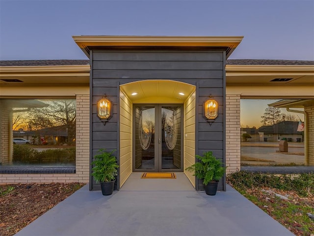 view of exterior entry with brick siding and french doors