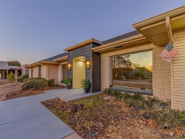 exterior entry at dusk featuring brick siding