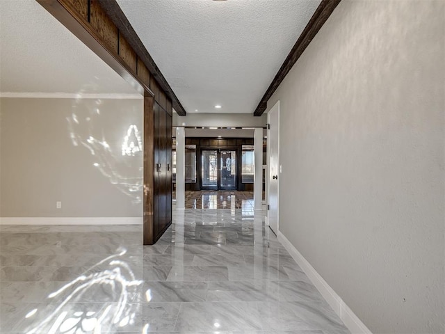 hall featuring ornamental molding, baseboards, marble finish floor, and a textured ceiling