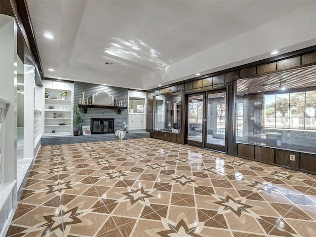 unfurnished living room with built in features, recessed lighting, a brick fireplace, and a textured ceiling