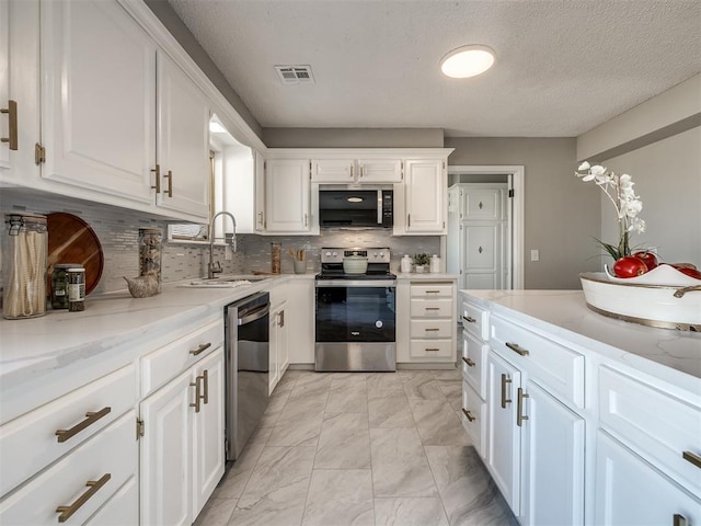 kitchen featuring appliances with stainless steel finishes, backsplash, light stone counters, sink, and white cabinets