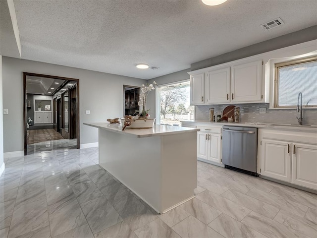 kitchen with visible vents, a sink, light countertops, white cabinets, and dishwasher