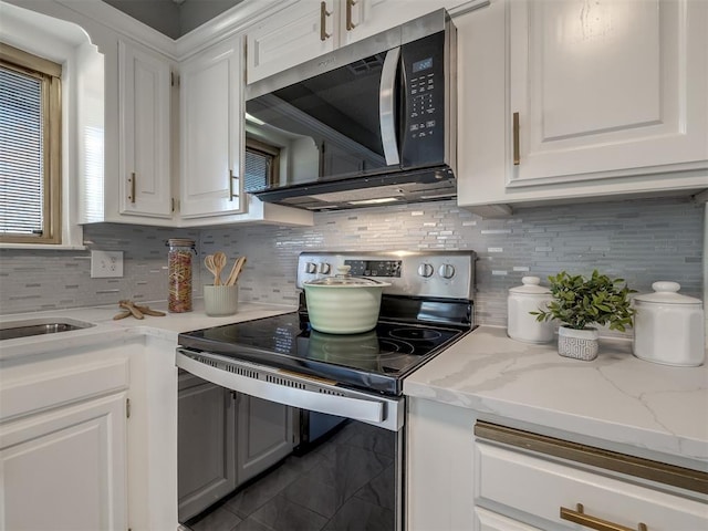 kitchen featuring backsplash, light stone countertops, white cabinets, and stainless steel appliances