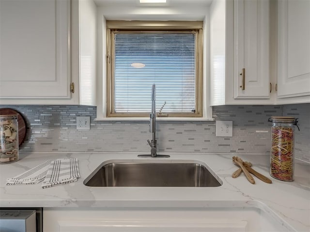 kitchen with decorative backsplash, light stone countertops, white cabinetry, and sink