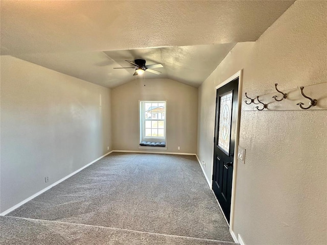 empty room featuring a textured ceiling, ceiling fan, dark carpet, and lofted ceiling