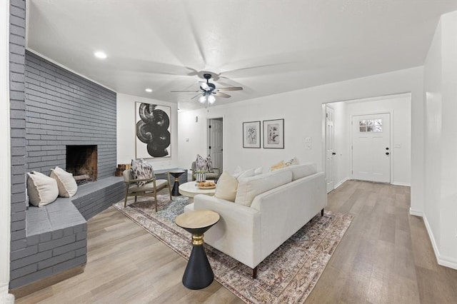 living room featuring light hardwood / wood-style floors, ceiling fan, and a fireplace