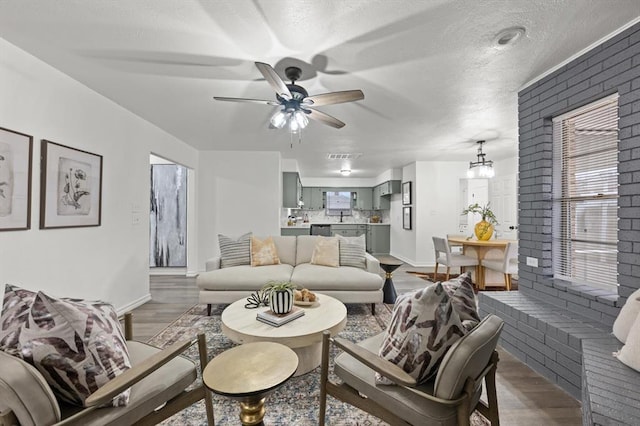 living room with a textured ceiling, ceiling fan with notable chandelier, and hardwood / wood-style floors