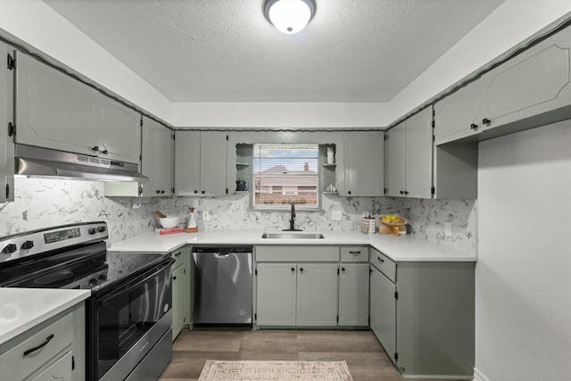 kitchen with appliances with stainless steel finishes, backsplash, dark hardwood / wood-style flooring, a textured ceiling, and sink