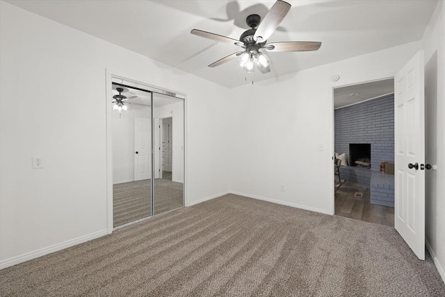 unfurnished bedroom with ceiling fan, a closet, a fireplace, and carpet flooring