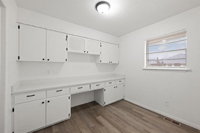 kitchen featuring hardwood / wood-style floors, white cabinets, and built in desk