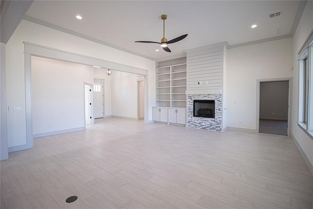 unfurnished living room with ceiling fan, light wood-type flooring, built in features, and a fireplace