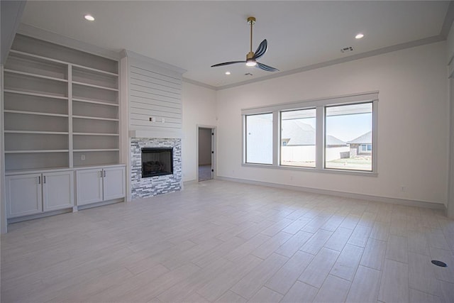 unfurnished living room with ceiling fan, crown molding, light hardwood / wood-style flooring, a stone fireplace, and built in shelves