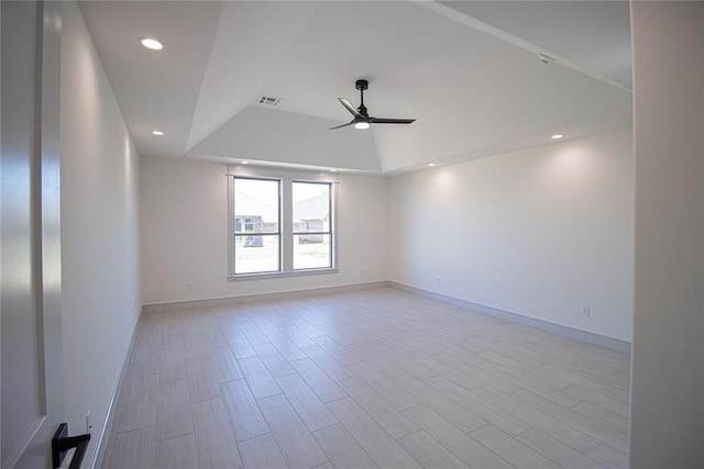 empty room featuring ceiling fan, light wood-type flooring, and a tray ceiling