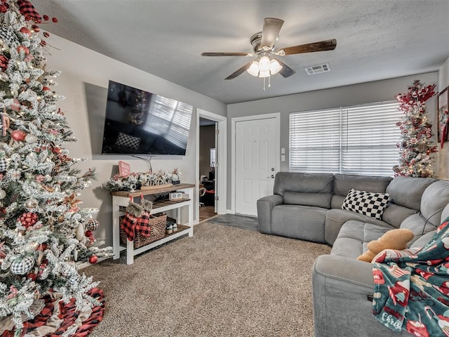 living room with ceiling fan, carpet floors, and a textured ceiling