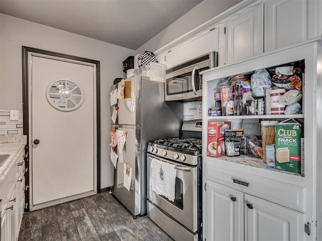 kitchen featuring light stone countertops, dark hardwood / wood-style flooring, decorative backsplash, white cabinets, and appliances with stainless steel finishes