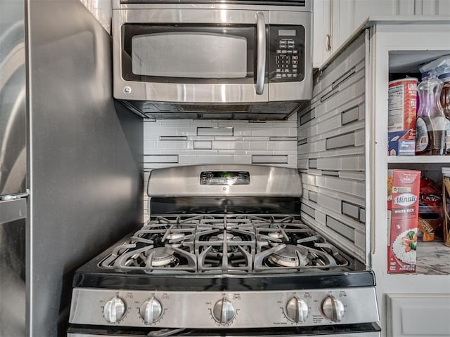 kitchen featuring decorative backsplash, white cabinetry, and stainless steel appliances