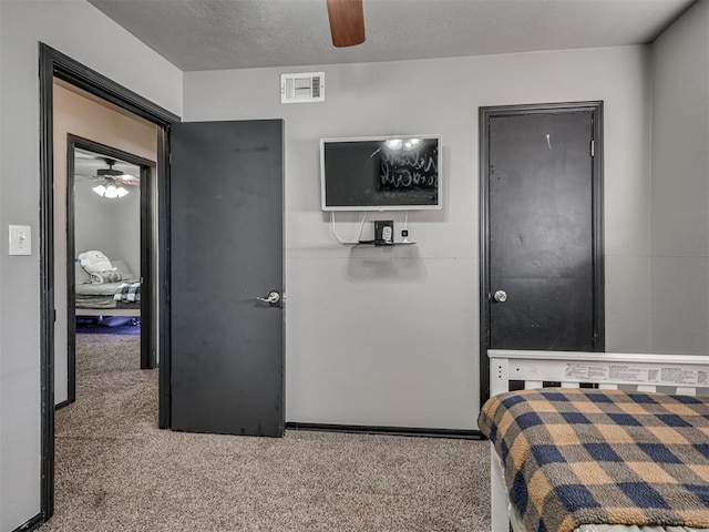 carpeted bedroom featuring ceiling fan and a textured ceiling