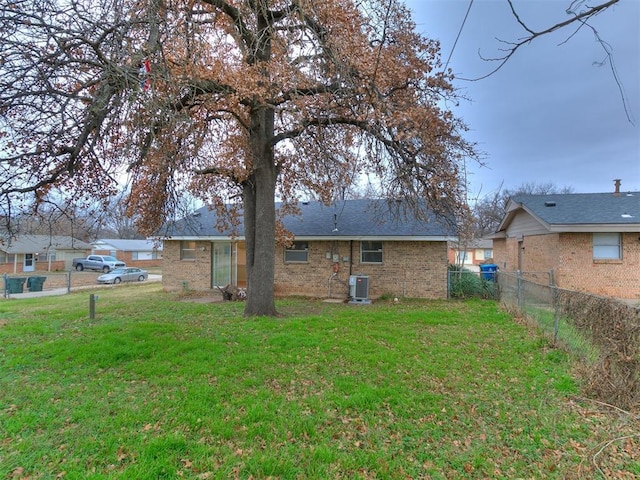 rear view of house with central air condition unit and a lawn