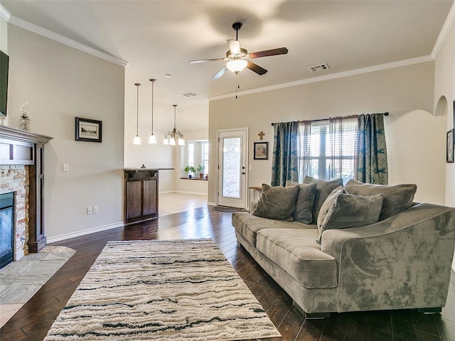 living room featuring crown molding, a fireplace, dark wood-type flooring, and ceiling fan with notable chandelier