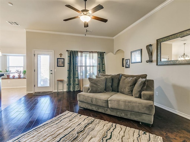 living room with dark wood-type flooring, ceiling fan with notable chandelier, and ornamental molding