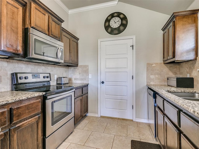 kitchen with light stone countertops, appliances with stainless steel finishes, tasteful backsplash, crown molding, and light tile patterned floors