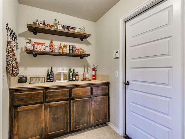 bar featuring dark brown cabinetry and light tile patterned floors