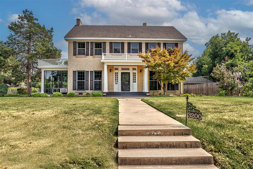 colonial inspired home with a balcony and a front yard